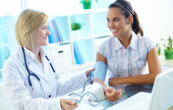 Doctor measuring patient’s blood pressure with digital monitor